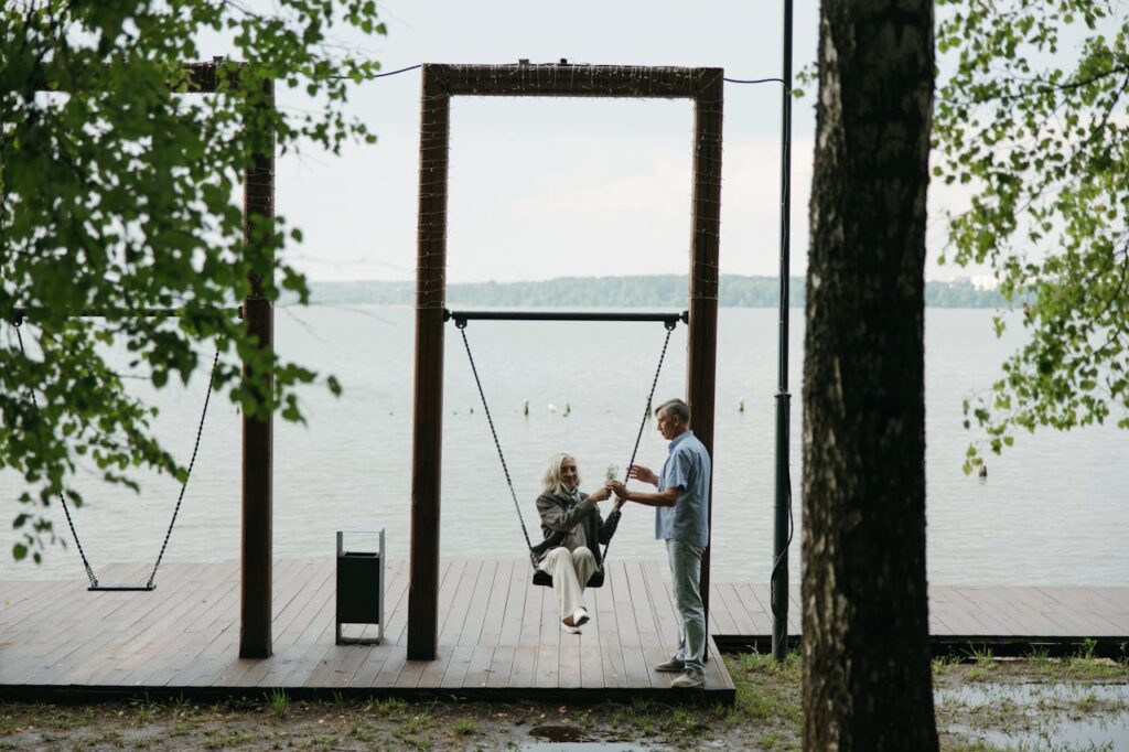 Senior couple bonding on a swing by a peaceful lakeside, capturing romance and togetherness.